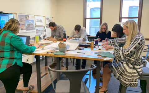 an image of the design charette for Blue Room House One that includes several people working around a table at Studio K2 Architecture.